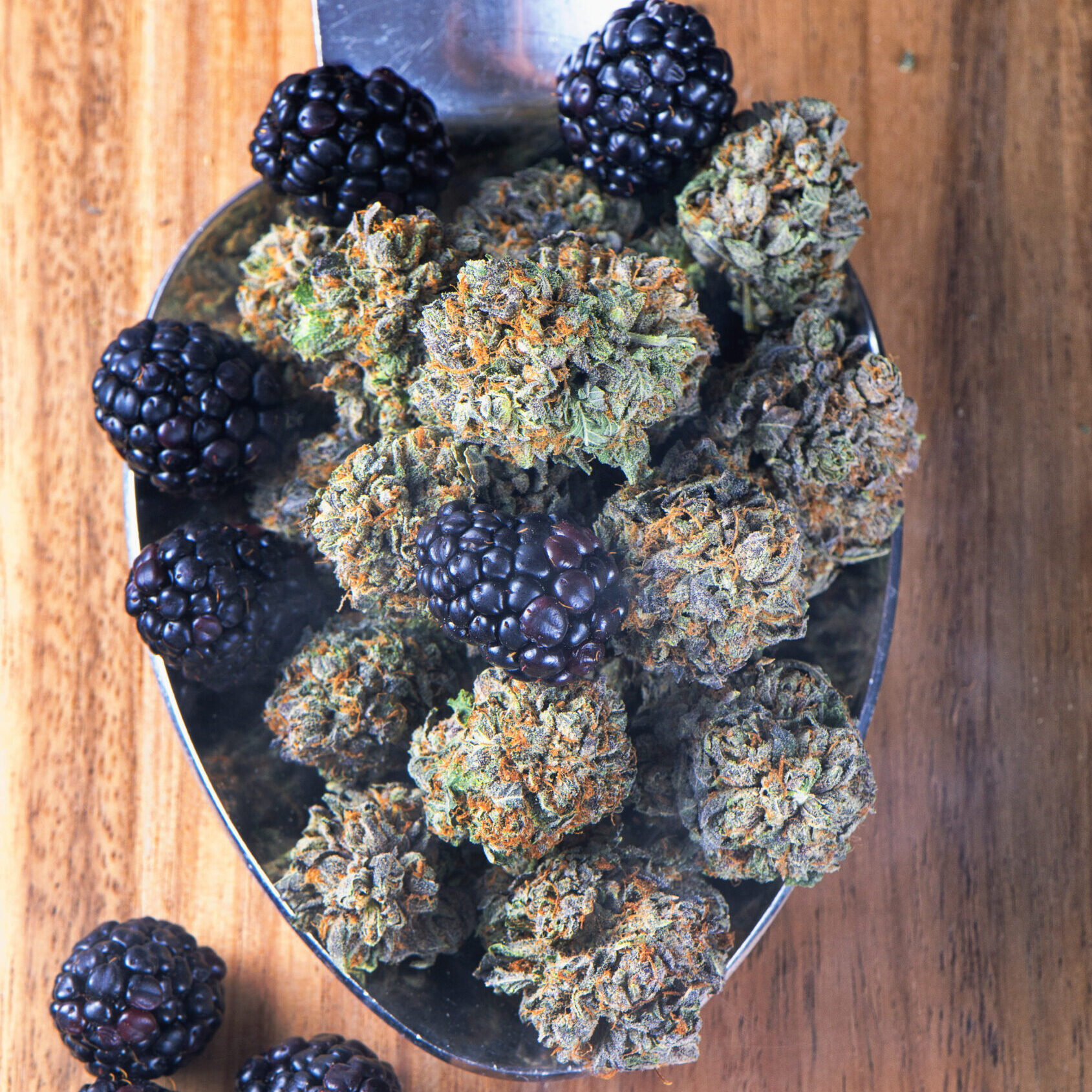 Berries and cannabis displayed on a wooden board